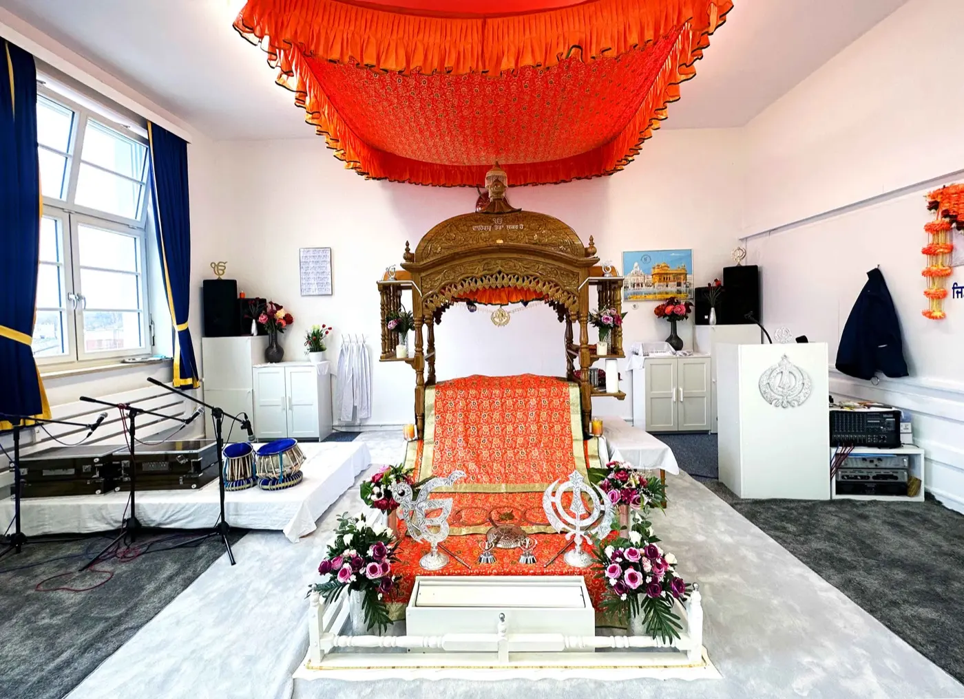 Darbar Sahib des Gurdwara Kiel: der Palki Sahib mit Guru Granth Sahib Ji unter einem orangefarbenen Baldachin